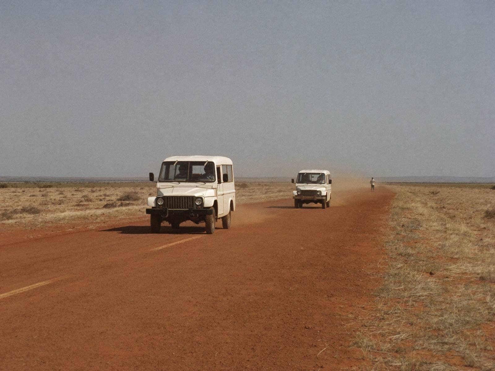 Field vehicles on a red earth road in northern Kenya