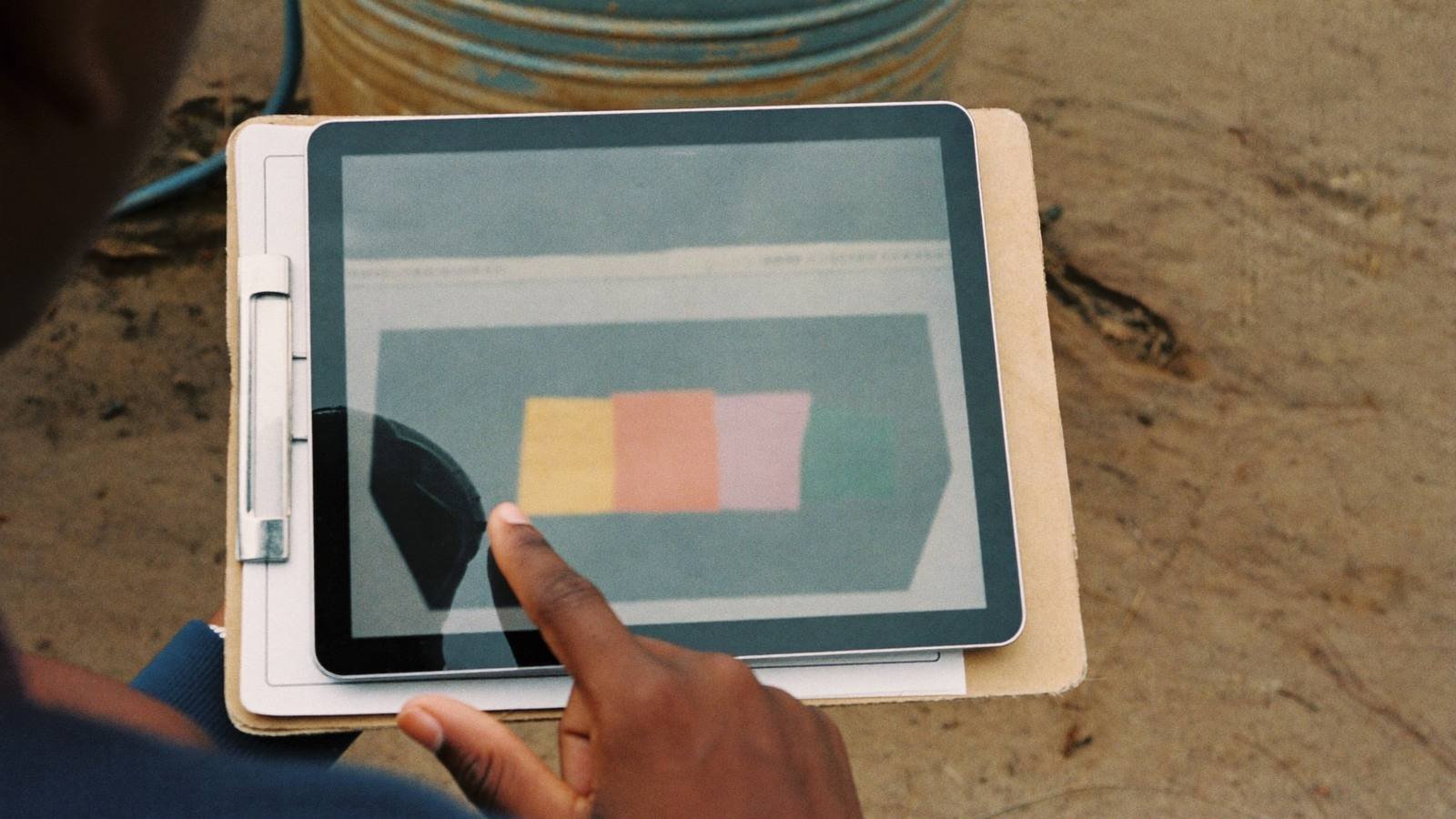 Hands holding a tablet with charts at a project site