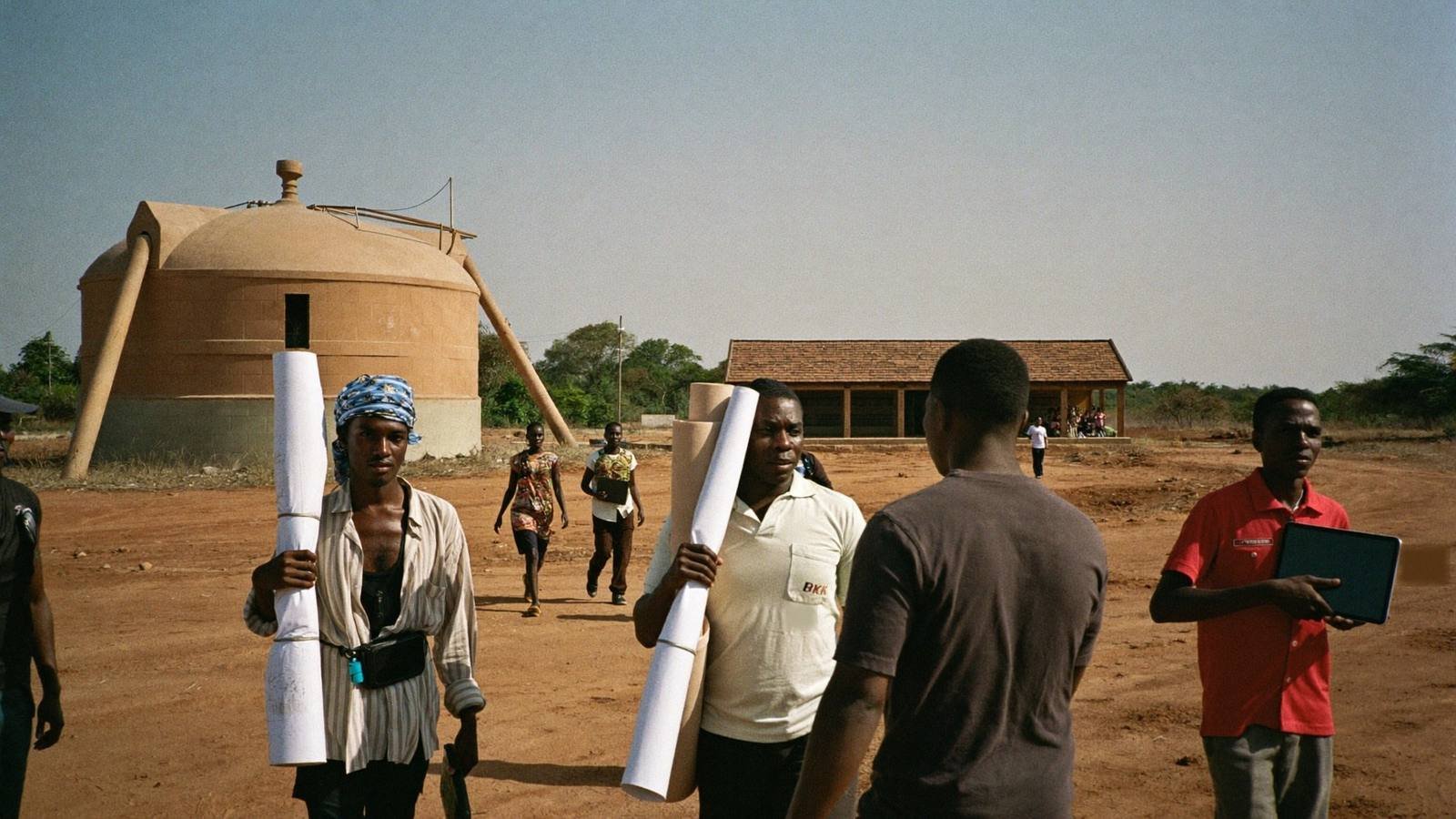 Project team walking across a site carrying drawings and a tablet